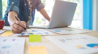 A business man working on wooden desk(table) with laptop and pen at office.